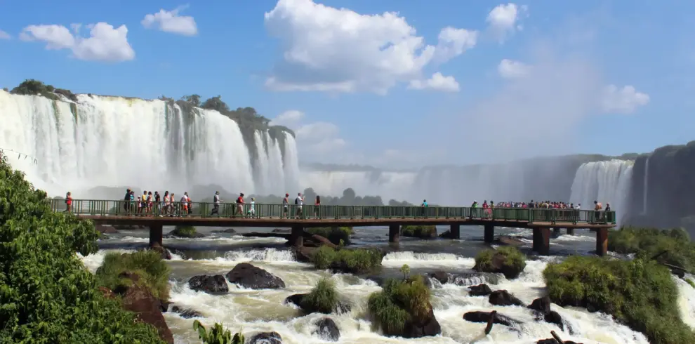 Tourists standing on bridge near Iguazu Falls enjoying scenic waterfall view