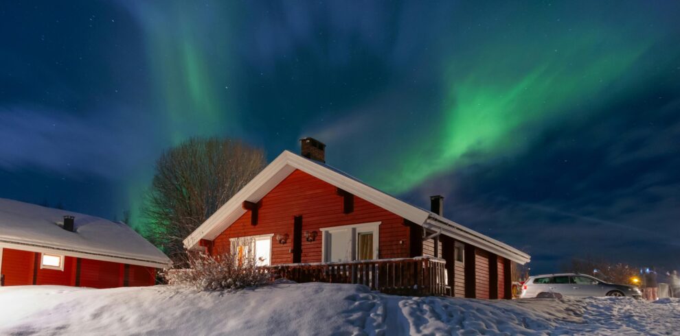 Aurora borealis over snowy cottage in Lapland during Iceland and Northern Lights tour