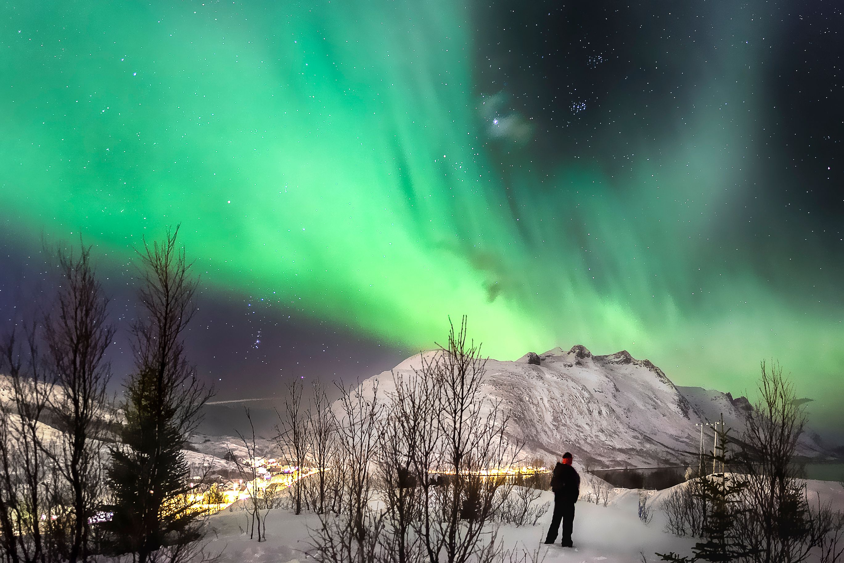Traveler watching the Northern Lights over a snowy Arctic landscape in Murmansk, Russia during the Aurora in Russia tour.