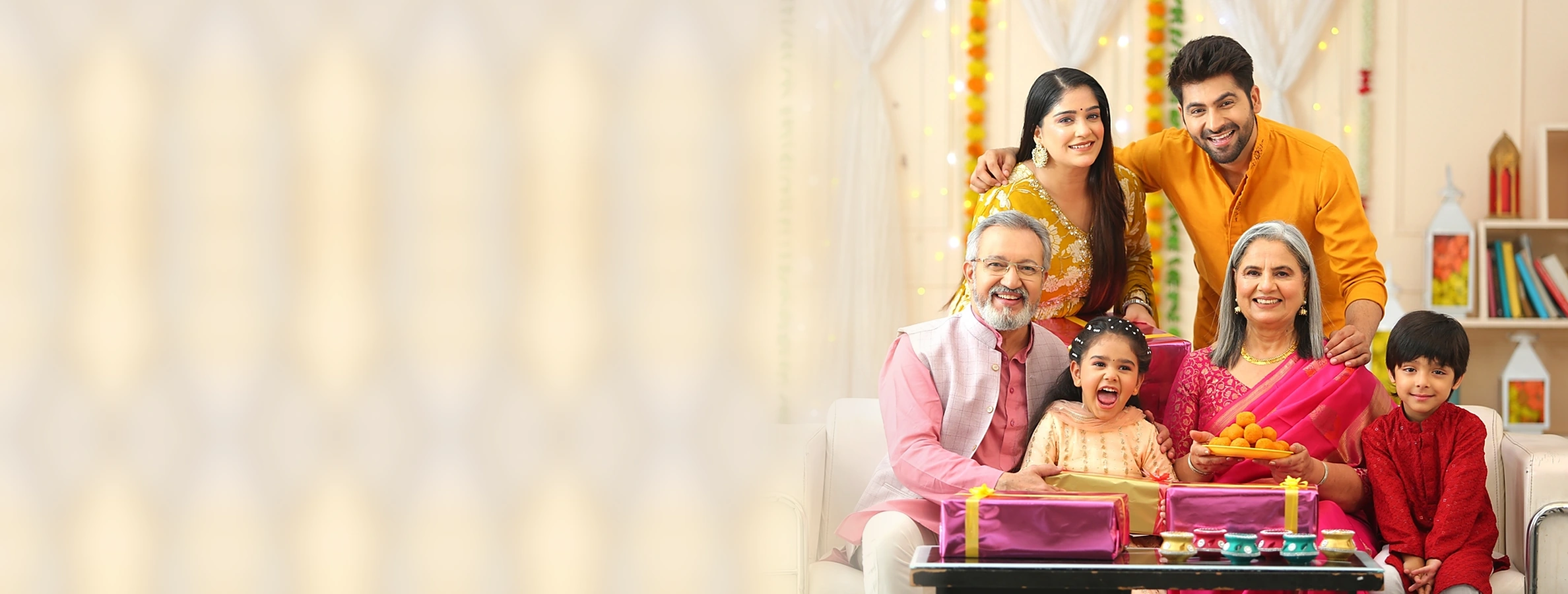 Happy Indian family celebrating Diwali together at home with sweets and gifts